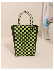 Detail of green and black checkered plastic woven bag with metal rivet handle fixings