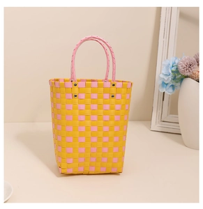 Close-up of yellow and pink plaid plastic woven handbag with pink circular handles