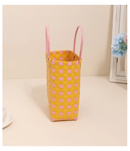 Detailed view of yellow and pink plaid woven storage basket with round pink handles