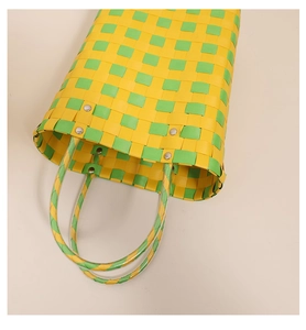 Close-up of yellow and green woven tote bag with durable handles and metal rivets