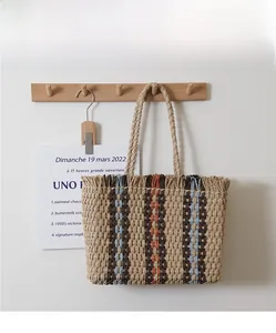 Detailed macro view of woven straw tote bag with colorful vertical stripes and fringe edge