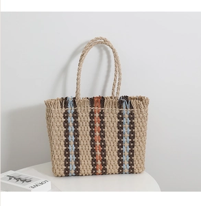 Detailed close-up of striped straw tote bag featuring natural fringe and woven handles