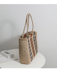 Detail of colorful vertical striped straw tote bag with round handles on white desk