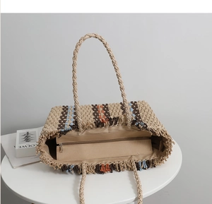 Detail of hand-woven straw tote with colorful stripes, fringe edges, and zipper lining