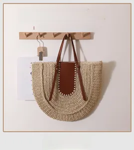 Detail of handcrafted large straw tote bag with brown leather handles and metal rivets