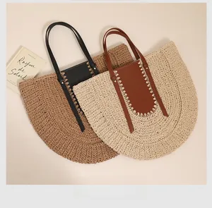 Detail view of woven straw tote bags with contrast leather panels and thick stitching