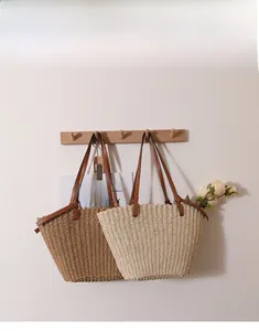 Détail d'un sac porté épaule en paille tressée avec lanières en cuir et texture naturelle