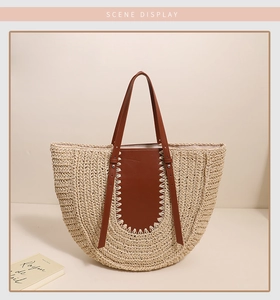 Detail of the woven straw tote with high-quality brown leather handles and stitching