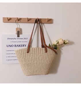 Détail de la texture tissée ondulée et des bandoulières en cuir marron du sac en paille