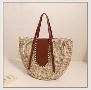 Close-up of semi-circle straw tote bag showing natural weaving and brown leather handle