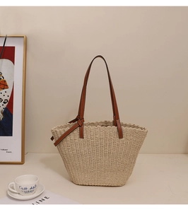 Détail du sac cabas en paille tressée avec anses en cuir marron et design minimaliste