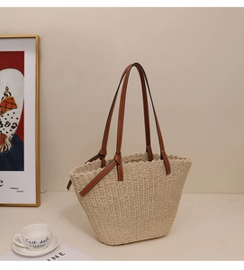 Détail d'un sac cabas en paille tressée beige avec poignées en cuir marron et coutures