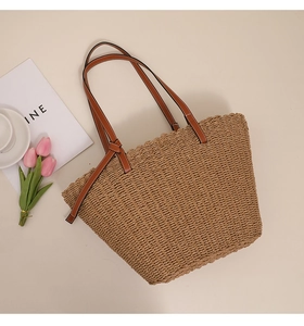 Détail du sac cabas en paille avec anses en cuir marron et design à bords ondulés