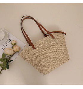 Détail d'un sac cabas en paille tissée avec anses en cuir marron et nœuds élégants