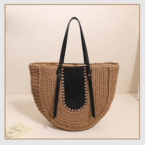Close-up of semi-circular straw bag with black leather stitching and woven texture