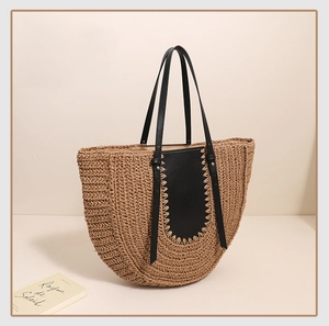 Detail of hand-woven straw tote bag featuring black leather trim and contrast stitching