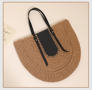 Detail of handwoven straw tote with black leather patchwork and sleek shoulder handles