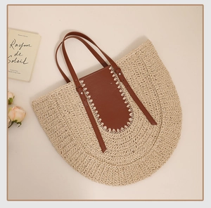 Detail of hand-stitched leather strap on large crescent straw tote bag for beach vacations