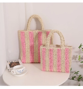 Detail view of two handmade woven straw tote bags with pink and beige vertical stripes