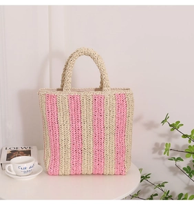 Detailed texture of handwoven pink and white vertical stripes on a straw beach bag