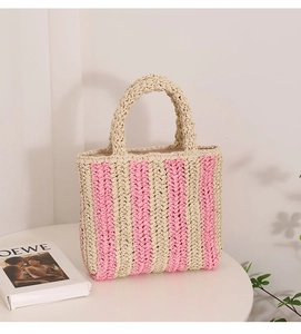 Detailed texture of pink and beige striped woven straw tote bag on a white table