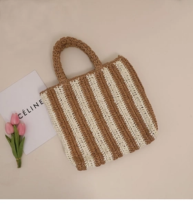 Close-up of a woven straw tote bag with vertical stripes and stylish top handles