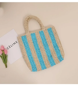 Close-up of a striped straw tote bag with blue and beige woven texture for beach vacation