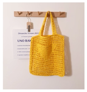 Detail of bright yellow crochet tote bag with large hollow mesh weave and soft dual handles