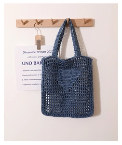 Macro detail of hand-woven hollow mesh net bag in blue-gray with comfortable wide straps