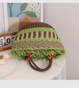Detail der Boho-Strohtasche mit grünen Fransen und bunten Holzperlen-Griffen