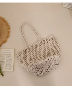 Close-up of beige woven cotton mesh beach tote bag with props on a warm background