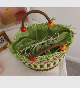 Detailaufnahme der Strohtasche mit grünen Quasten, Holzperlen und praktischem Kordelzugfutter