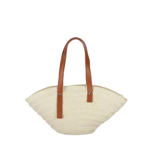 Detail of hand-woven straw beach bag with brown leather handles and metal rivets