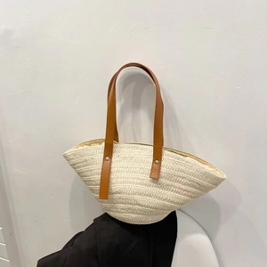 Detail of hand-woven straw tote with brown leather strap and soft fabric lining