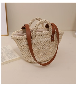 Detail of hand-woven corn husk straw bag with brown leather strap and fabric lining