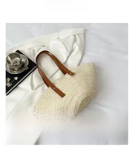Detail of hand-woven straw tote bag with concentric circle texture and brown handles