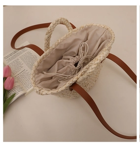 Detail view of woven corn husk basket bag with drawstring liner and brown leather strap