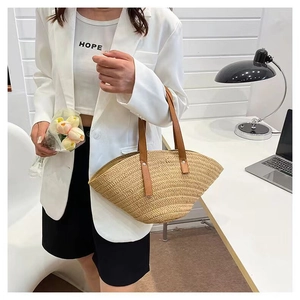 Detail of woven straw tote bag with brown leather handles and secure metal rivets
