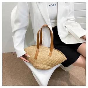 Detail of handwoven seashell-shaped straw bag with brown leather handles for summer