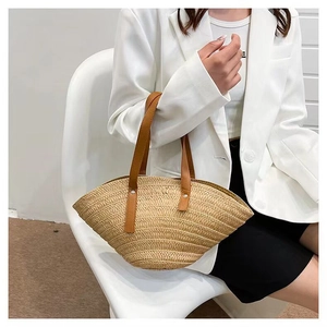 Detail of hand-woven shell straw bag with premium leather handles and silver rivet accents