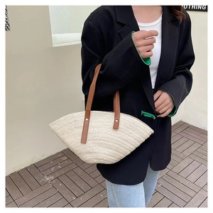 Detail of fan-shaped straw bag with dark brown leather handles and woven texture