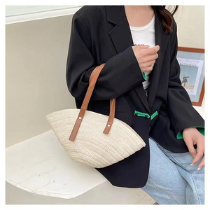 Detail of fan-shaped straw tote bag with brown leather handles and green lining