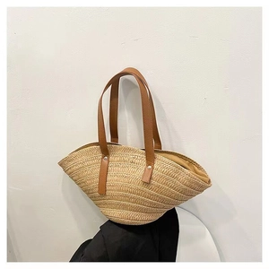 Detail of handmade straw beach bag with brown leather handles and metal rivet fasteners