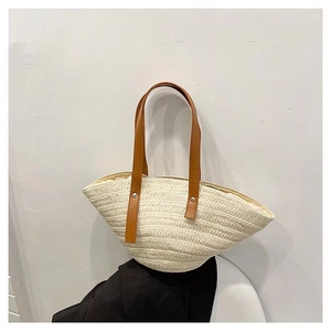 Detail of shell-shaped straw bag with cream woven fibers and brown leather handles