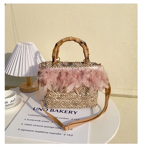 Detail of straw woven bag featuring pink feather trim, bamboo handle and polka dot lining