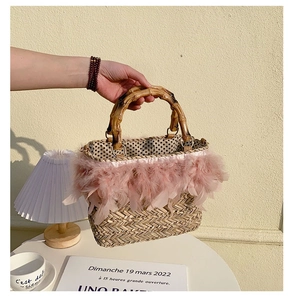 Detail of handmade straw bag featuring pink feathers and natural bamboo handles