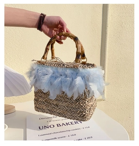 Detail of straw bag with blue feathers, bamboo handle, and polka dot drawstring lining