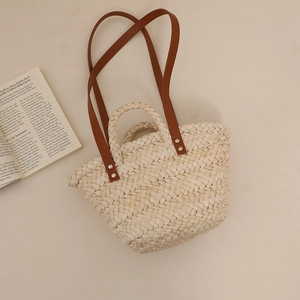Handcrafted corn husk woven tote bag with brown leather straps and metal rivets