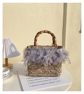Detail of straw bag featuring chic feather trim and natural bamboo handles for vacation