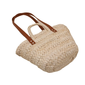 Handwoven corn husk basket bag with brown leather shoulder straps and dual handles